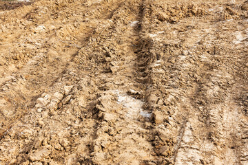 Tyre track and human footprint on sand texture background. Traces of off-road tires. Cracked earth on country road with traces of tires, cars, cracks and dirt. To use as background