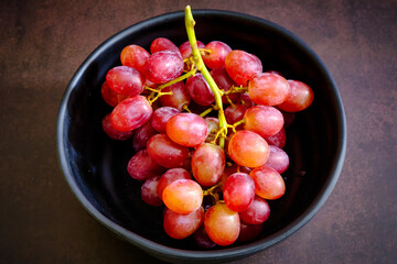 Red delicious fresh grapes on a black bowl. ready to eat