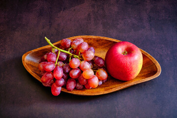 Red delicious fresh grapes and apple on a wooden bowl. ready to eat