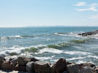 Panoramic seascape. Huge stormy waves crashing into huge stones near the city’s Black Sea embankment. City buildings of Odessa on horizon