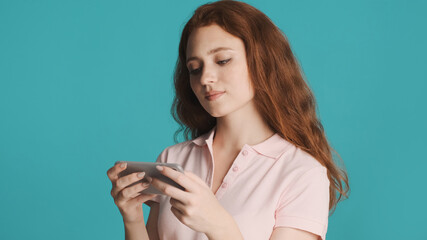 Attractive girl intently watching video on smartphone over colorful background