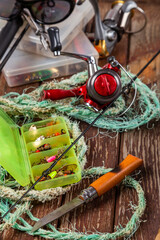 Different fishing tacles with rod and reels on wooden brown background.