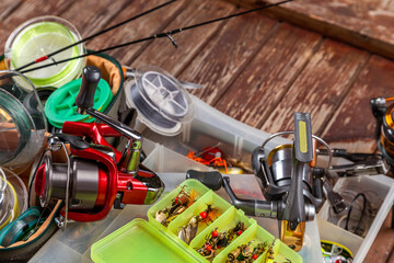 Different fishing tacles with rod and reels on wooden brown background.