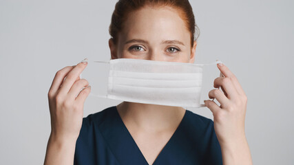 Young attractive doctor wearing medical mask on camera over white background. Safety concept