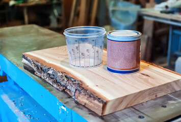 epoxy resin and measuring container in a carpentry shop. Making furniture with epoxy resin