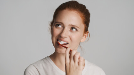Attractive girl brushing teeth on camera over white background