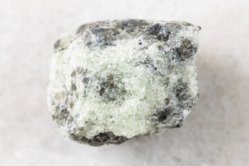 closeup of sample of natural mineral from geological collection - unpolished saccharoidal Apatite rock on white marble background from Khibiny, Kola Peninsula, Russia