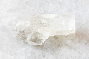 closeup of sample of natural mineral from geological collection - unpolished Petalite rock on white marble background from Araguai, Brazil