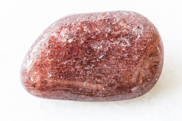 closeup of sample of natural mineral from geological collection - polished red aventurine gem stone on white marble background from Canada