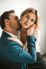 An office worker sits on a colleague's lap. Man kissing a girl on the neck. Workplace romance concept. High quality photo.