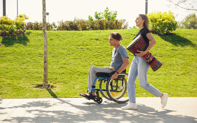 Enjoying life. Happy caucasian handicapped man on a wheelchair spending time with friends playing...