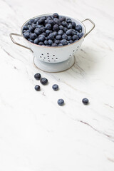 Freshly Picked Blueberries in a White Colander on a White Countertop