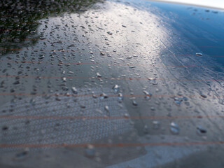 Droplets on glass of car with blur woman floppy hat background, concept of travel in rainy day.