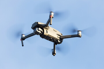 Drone with camera flying over blue sky background