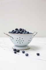Freshly Picked Blueberries in a White Colander on a White Countertop