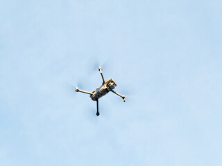 Drone with camera flying over blue sky background