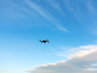 Drone with camera flying over blue sky background