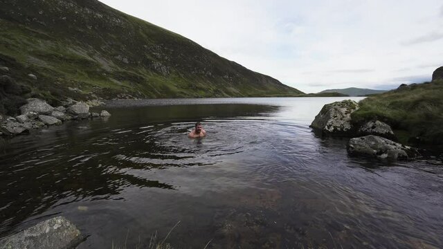 A man skinny dipping in a mountain lake