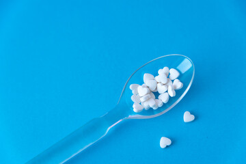 Fototapeta na wymiar pills in spoon close up on blue background 