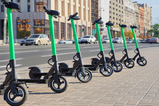 Eco transportation concept. Scooter rental in the city. Environment conservation. Eco friendly transportation. Vehicle rent service concept. Electric scooters in line on urban city background