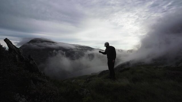 A man drinking tea in a wild magical mountain scene in Wales UK