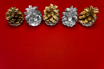 Fototapeta na wymiar New year 2021. Pine-tree cones golden and silver colors above red Christmas background.
