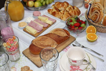 Buffet breakfast table filled with fruits, cereals, orange juice, snacks, breads, sweets, hot coffee and milk. Balanced diet.