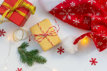 Festive Christmas flat lay with Santa hat, cookies, gift and bokeh lights.