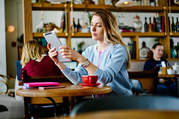 Young woman using tablet to read book at cafe