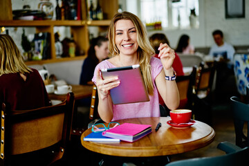 Happy young woman using tablet in cafe