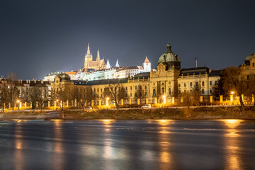 Fototapeta na wymiar two most important buildings in Prague over Vltava river. Strakova Akademie in foreground is the seat of the Government of the Czech Republic, Prague Castle in background is the seat of the president