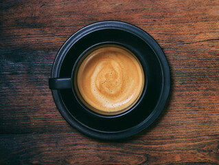 A cup of coffee on wooden desk background, top view