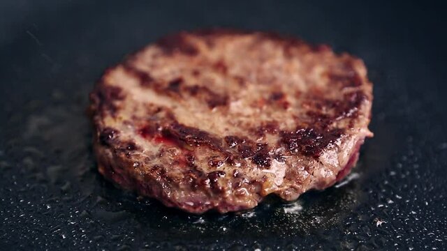 Natural beef meat cutlet frying on hot pan in close up video clip.Delicious ground minced meat being fried for hamburger dish in restaurant kitchen