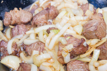 Cooking pilaf in a cauldron on the grill outside in the summer