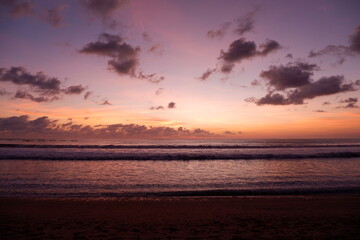 A dramatic sunset view on Kuta beach, Bali, with gradations of purple, orange and blue sky