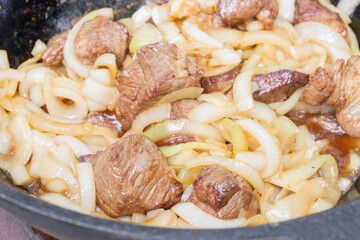 Cooking pilaf in a cauldron on the grill outside in the summer