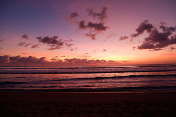 A dramatic sunset view on Kuta beach, Bali, with gradations of purple, orange and blue sky