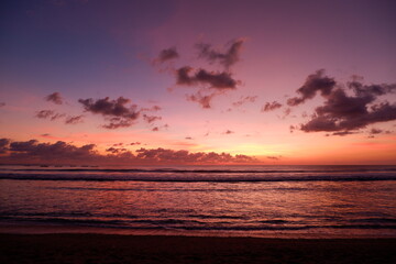 A dramatic sunset view on Kuta beach, Bali, with gradations of purple, orange and blue sky
