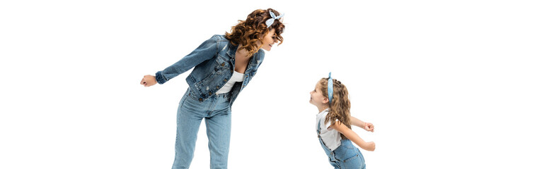 mother and daughter in denim outfits looking at each other isolated on white, panoramic shot