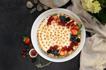 Homemade birthday cake cheesecake with protein cream garnished with fresh berries in a white plate on a black table