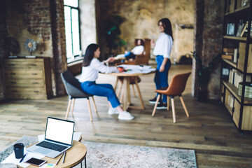 Laptop on small table in loft office with women chatting
