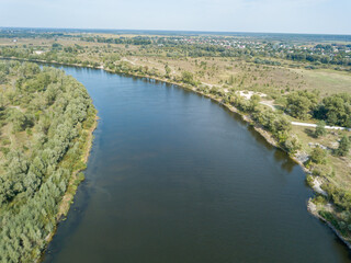 Aerial drone view. The bend of a wide river among green meadows. Sunny summer day.