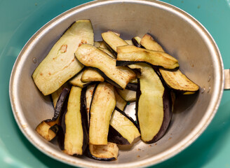 Sliced eggplant for frying in a pan.