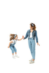 daughter in denim outfit jumping and clapping hands with mother isolated on white