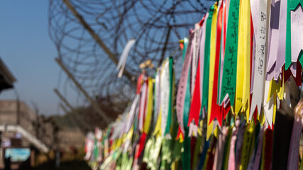 Prayer ribbons attached to a barb wire fence at the Korean Demilitarized Zone - obrazy, fototapety, plakaty