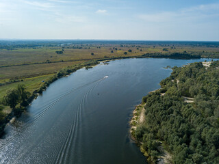 Aerial drone view. The bend of a wide river among green meadows. Sunny summer day.