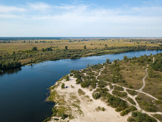 Green banks of a country river. Aerial drone view, sunny summer day.