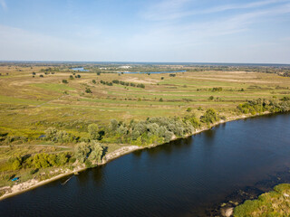 Fototapeta na wymiar Green banks of a country river. Aerial drone view, sunny summer day.