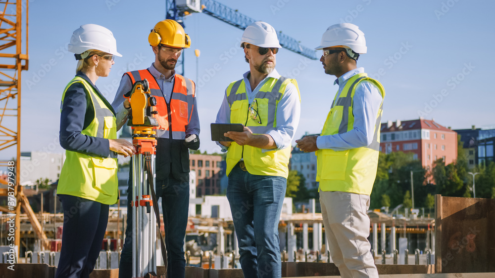 Wall mural Diverse Team of Specialists Use Tablet Computer on Construction Site. Real Estate Building Project with Civil Engineer, Architect, Business Investor and Surveyor with Theodolite Discussing Plans.