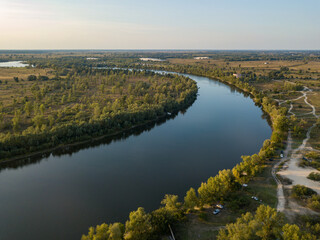 Aerial drone view. The bend of a wide river among green meadows. Sunny summer day.